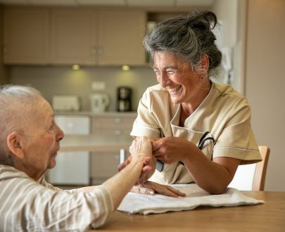 Complicité entre une résidente et une soignante dans cuisine d'une unité de vie d'Ehpad